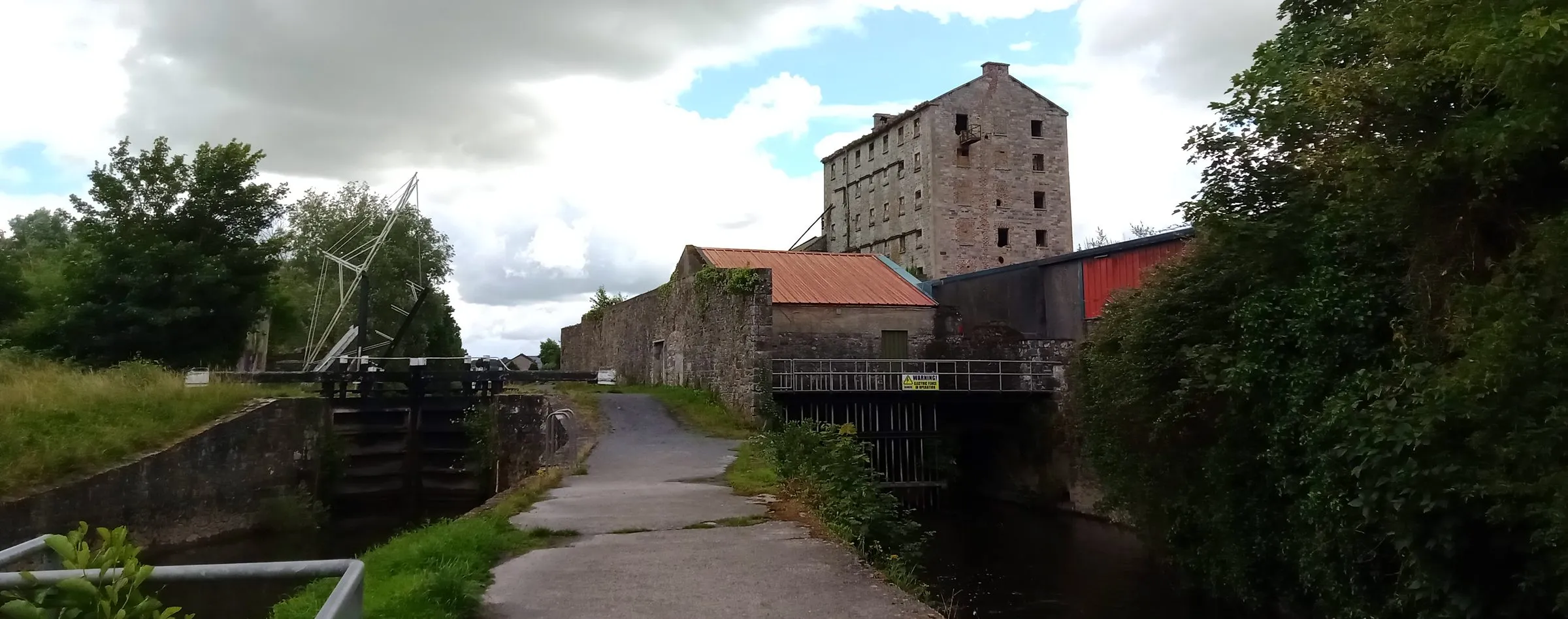 The lock and five-storey stone mill at Bagenalstown seen from the Barrow Way, with the lifting-bridge gear beside the lock gates and the towpath running between them