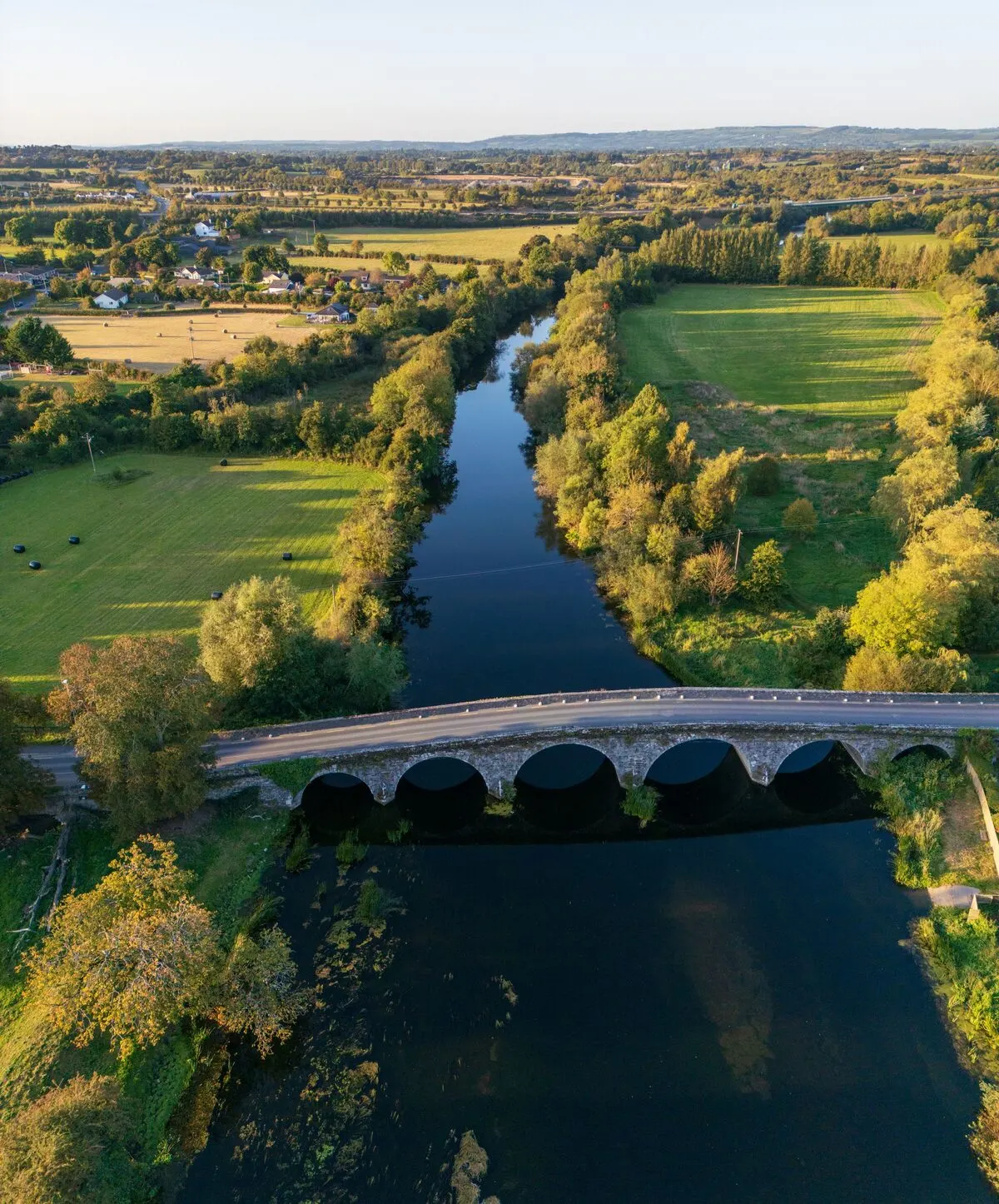Bennettsbridge seen from the air, its seven-arch stone bridge crossing the River Nore with the valley's farmland behind