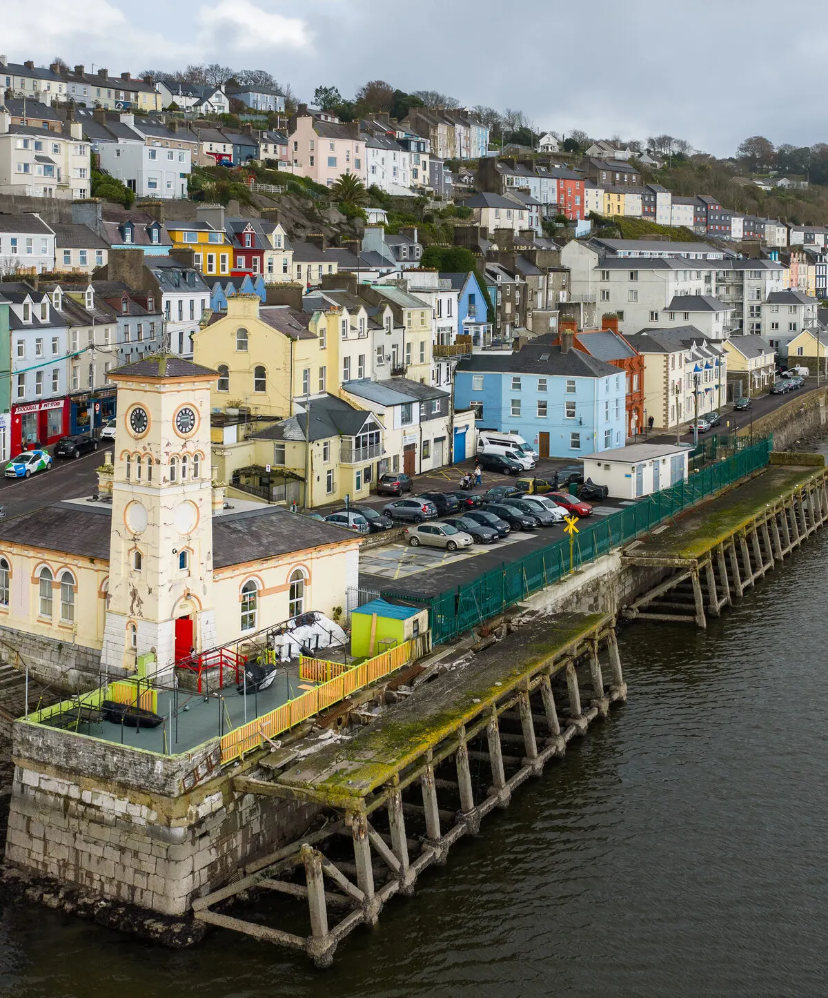 The clock tower of the old town hall on its pier at Cobh, with the quay and the terraces of painted houses rising up the hill behind