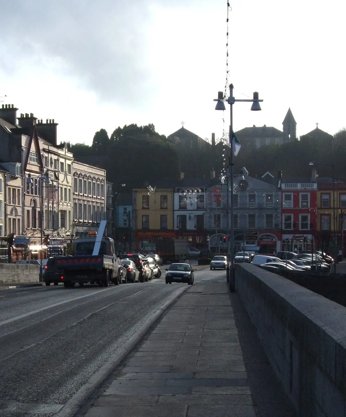 The bridge over the River Blackwater at Fermoy, looking across the parapet to the painted shopfronts of the town and a church spire behind