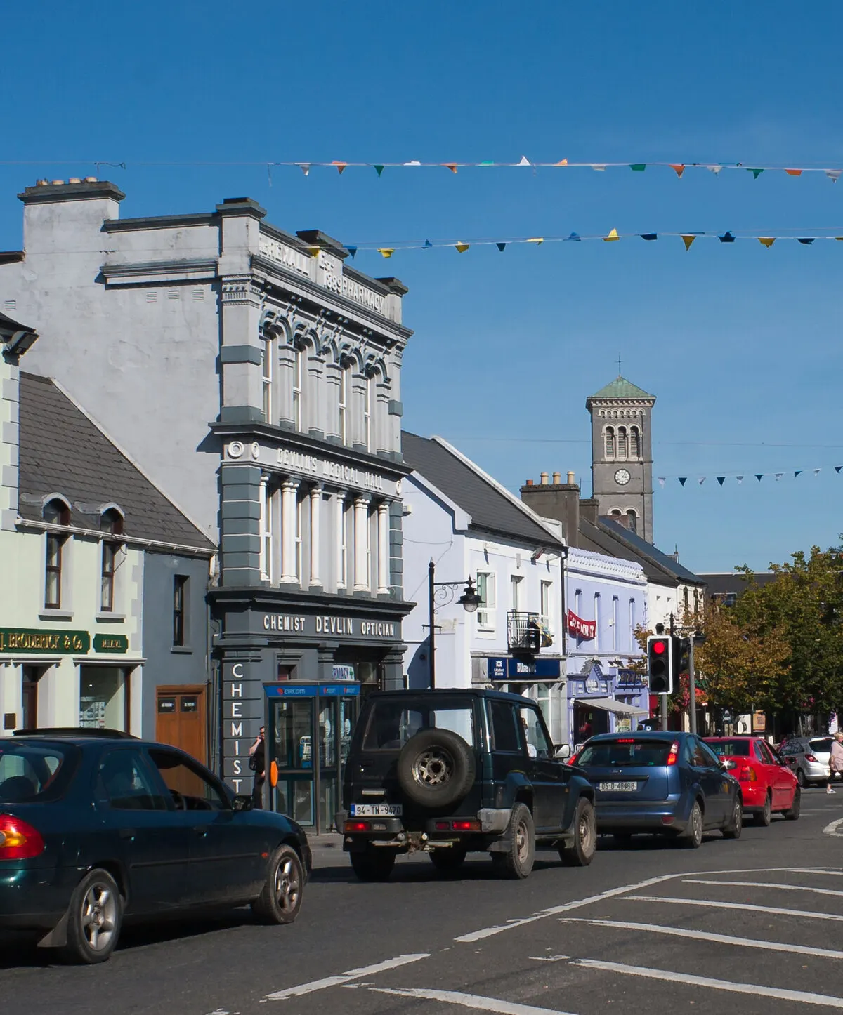 Liberty Square in Thurles, its shopfronts and parked cars under lines of bunting, with the cathedral campanile rising beyond
