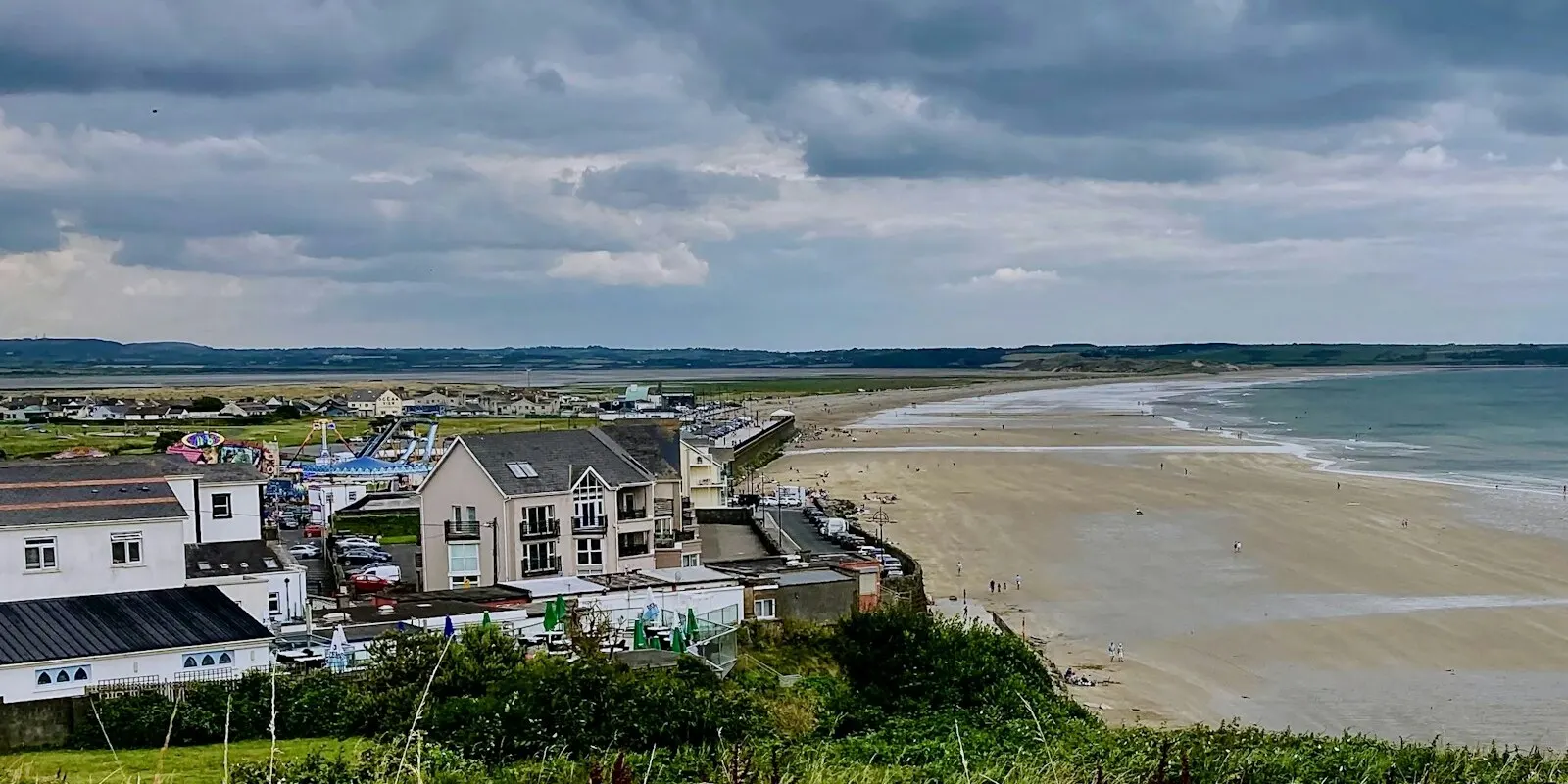 Tramore strand seen from the hill above the town, with the seafront terrace and amusements along the left
